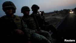 FILE - Soldiers sit atop a military vehicle as they arrive for an operation to destroy a poppy field in the municipality of Coyuca de Catalan, Mexico, April 18, 2017.