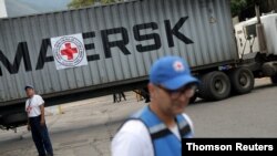 Volunteers stand near a container truck bearing a logo of the International Federation of Red Cross and Red Crescent Societies that arrived carrying humanitarian aid, in Caracas, Venezuela, July 31, 2019.