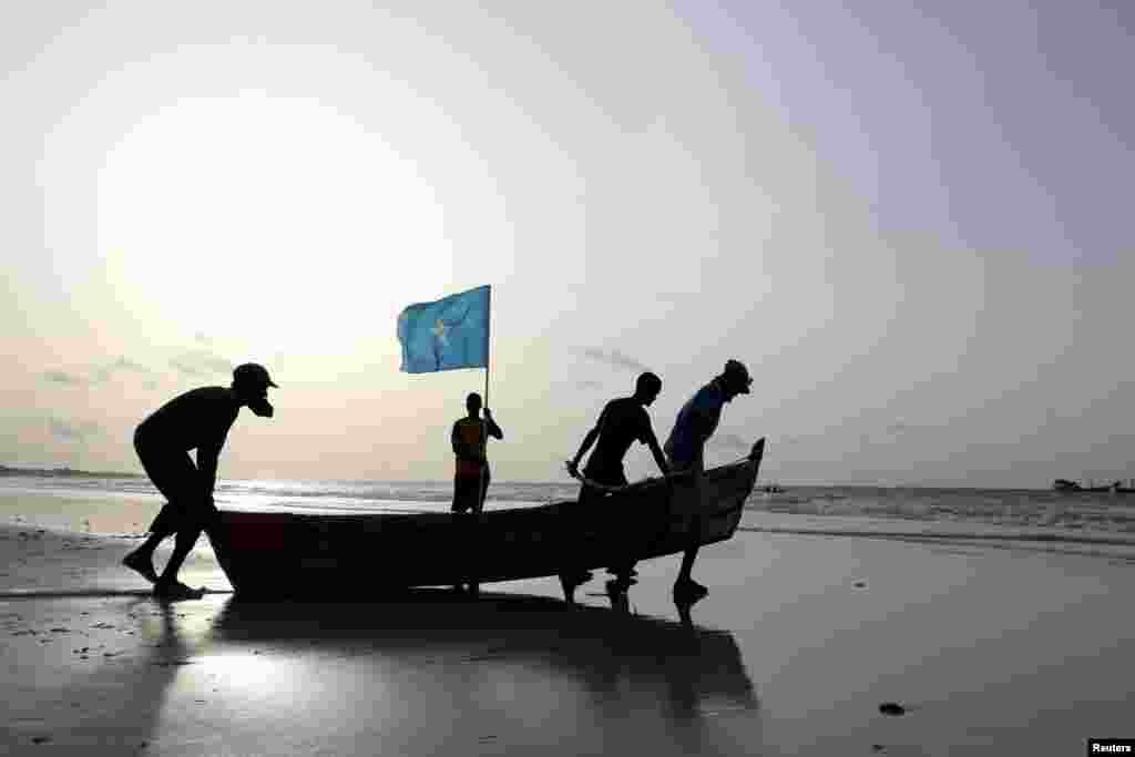 Fishermen carry a boat in to the water in Lido beach, Mogadishu&#39;s Abdiaziz District, Somalia 