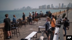 People stand still as a two-minute siren sounds in memory of victims of the Holocaust, in Tel Aviv, Israel, April 8, 2021. 