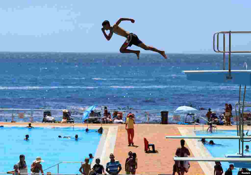 A person dives from a springboard during a hot summer day at Sea Point swimming pool in Cape Town, South Africa.