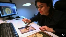 Christina Sotirakoglou a handwriting expert, observes Byzantine paintings based on photographs prints, at her office, in Thessaloniki, northern Greece, Saturday, Nov. 30, 2024. (AP Photo/Giannis Papanikos)