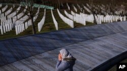 FILE - A Bosnian Muslim woman prays next to the monument with names of those killed in the Srebrenica genocide, at the Srebrenica Memorial Center, on International Holocaust Remembrance Day, in Potocari, Bosnia, January 27, 2024.