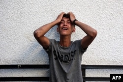 A Palestinian youth reacts upon seeing the bodies of relatives killed in an overnight Israeli airstrike in the Jabalia refugee camp in the northern Gaza Strip, Oct. 12, 2024.