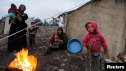 Displaced Syrian women and children, who fled from southern Idlib, gather around a fire in Afrin, Syria, Feb. 6, 2020. 