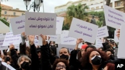 FILE - Women activists chant slogans and hold banners during a protest condemning violence against women and impunity, in Tunis, Tunisia on Friday, December 10, 2021. Banners in Arabic read: "Dig the graves and listen to the (killed) women".