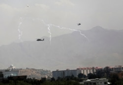 Anti-missile decoy flares are deployed as U.S. Black Hawk military helicopters and a dirigible balloon fly over the city of Kabul, Afghanistan, Aug. 15, 2021.