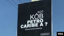 Yon ansèy nan yon poto nan Pòtoprens ki ekri yon kesyon, "Kot Kòb Petro Caribe a." 