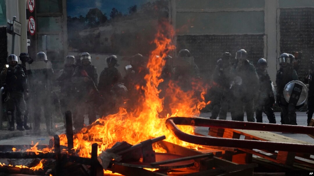 Police face a burning barricade during protests, Sept. 21, 2019, in Hong Kong. 