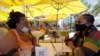 Anita Anderson, a la izquierda, de Grand Rapids, Michigan, y su sobrina Tawnya Heggins de Houston, conversan mientras cenan frente a un restaurante en Miami Beach, el famoso South Beach de Florida, el viernes 26 de junio de 2020. 