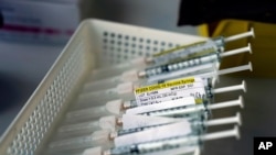 Syringes containing the Pfizer-BioNTech COVID-19 vaccine sit in a tray in a vaccination room at St. Joseph Hospital in Orange, Calif., on Jan. 7, 2011. Taking a new direction to speed re