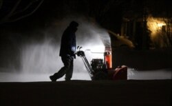 Roger Hake recibe ayuda de las luces de su camión mientras quita la nieve de la entrada antes de que salga el sol en Webster, cerca de Rochester, Nueva York, EE.UU., el 16 de febrero de 2021. Jamie Germano / Rochester Democrat y Chronicle / USA Today