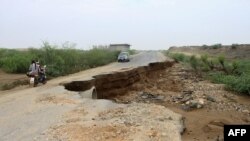 A motorcycle and a car drive through a road destroyed by flash floods in Yemen's northwestern Abs region in the Hajjah governorate, on Aug. 9, 2024.
