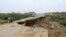 A motorcycle and a car drive through a road destroyed by flash floods in Yemen's northwestern Abs region in the Hajjah governorate, on Aug. 9, 2024.