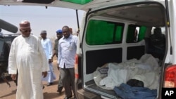 Ibrahim Gaidam, Governor of Yobe state, left, looks at bodies of students inside an ambulance outside a mosque in Damaturu, Nigeria, Tuesday, Feb. 25, 2014. Islamic militants killed dozens of students in a pre-dawn attack Tuesday on a northeast Niger