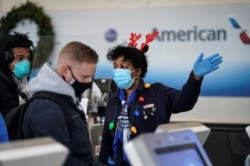 An airline worker in Christmas themed attire assists travelers at Ronald Reagan Washington National Airport in Arlington, Virginia, Dec. 28, 2020.