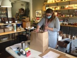 Anna Landmark gathers products together for an online order of local foods to be delivered, in Madison, Wisconsin. Her business switched from making cheese to distributing and delivering products to make up for lost revenue due to COVID-19 measures.