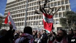 FILE - Anti-government protesters chant slogans, during ongoing protests against the Lebanese government in front of the Central Bank, in Beirut, Lebanon, Feb. 1, 2020.