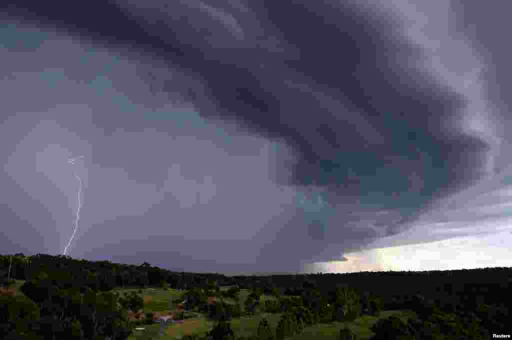 Lightning can be seen during a large storm in a neighborhood of Sydney, Australia. A severe thunderstorm hit parts of Sydney on Friday afternoon and damaged more than 100 properties.