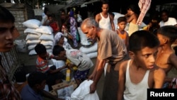 Warga Rohingya berbagi bantuan makanan dari World Food Program di kam Thae Chaung di Sittwe, Rakhine, 2014. (Foto: Dok)