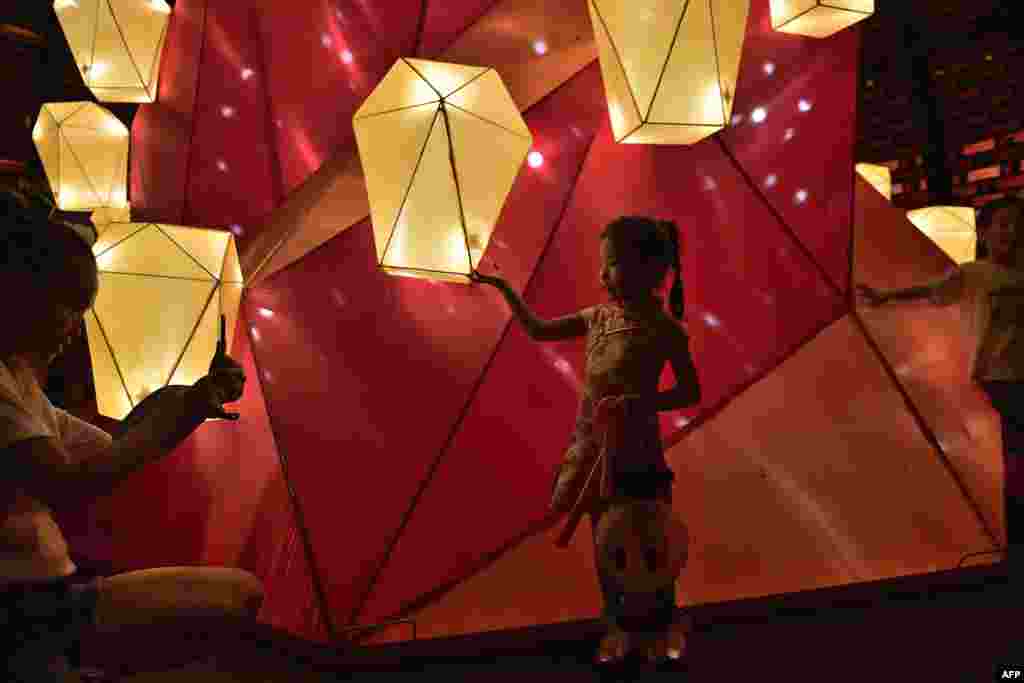 A girl poses for a picture next to a lantern display during mid-autumn festival celebrations at Victoria park in Hong Kong.