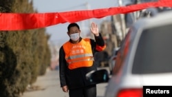 A village committee member stops a car for checking as he guards the entrance of a community amid China's battle against a new coronavirus, in Tianjiaying village, outskirts of Beijing, China, Jan. 29, 2020. 