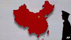 FILE - A security guard stands close to an electronic screen featuring a map of China.