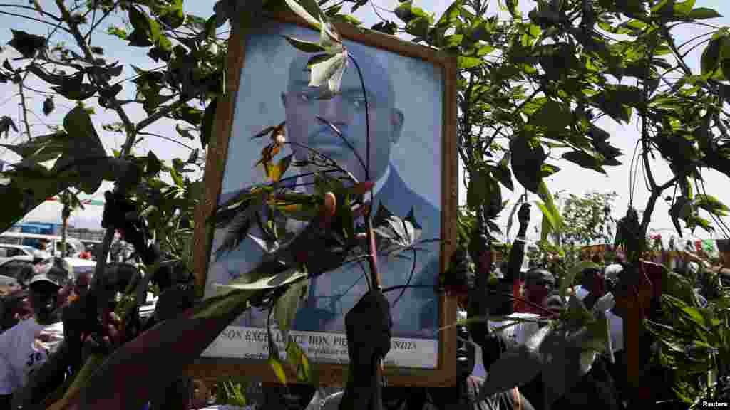 Des partisans du président Pierre Nkurunziza tiennent son effugie et des branches d&#39;arbre, à l&#39;annonce de son retour au palais présidentiel à Bujumbura, Burundi, vendredi 15 mai 2015.