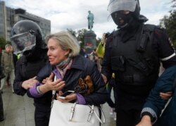 FILE - Police officers detain a woman during an unsanctioned rally in the center of Moscow, Russia, Aug. 3, 2019.