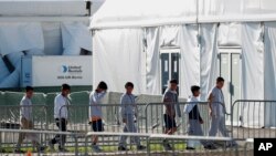 FILE - Youngsters line up to enter a tent at the Homestead Temporary Shelter for Unaccompanied Children in Homestead, Fla., Feb. 19, 2019.