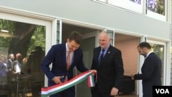 Hungarian State Secretary for Economic Strategy László György, left, cuts a ribbon, styled after the Hungarian flag, as Ambassador László Szabó, center, looks on at the opening ceremony of a business promotion center in Washington, June 12, 2019.