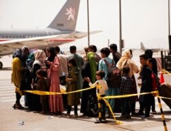 In this photo provided by the U.S. Marine Corps, civilians prepare to board a plane during an evacuation at Hamid Karzai International Airport, Kabul, Afghanistan, Aug. 18, 2021. (Staff Sgt. Victor Mancilla/U.S. Marine Corps via AP)