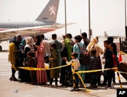 In this photo provided by the U.S. Marine Corps, civilians prepare to board a plane during an evacuation at Hamid Karzai International Airport, Kabul, Afghanistan, Aug. 18, 2021. (Staff Sgt. Victor Mancilla/U.S. Marine Corps via AP)