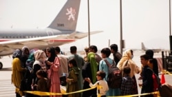 In this photo provided by the U.S. Marine Corps, civilians prepare to board a plane during an evacuation at Hamid Karzai International Airport, Kabul, Afghanistan, Aug. 18, 2021. (Staff Sgt. Victor Mancilla/U.S. Marine Corps via AP)
