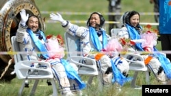 Astronot China (dari kiri) Zhang Xiaoguang, Nie Haisheng dan Wang Yaping melambaikan tangannya sesaat setelah mendarat dengan kapsul yang dibawa oleh pesawat antariksa Shenzhou-10 di wilayah Mongolia, China (26/6).