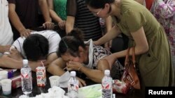The parents (bottom) of Wang Linjia, one of the two girls killed during the Asiana Airlines plane crash on Saturday, cry at a middle school in Quzhou, Zhejiang province, July 7, 2013. An emergency vehicle rushing to the scene of the Asiana Airlines crash 