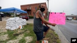 Michael Bledsoe sells sandbags as Tropical Storm Isaias approaches in Wilmington, N.C., Monday, Aug. 3, 2020. (AP Photo/Gerry Broome)