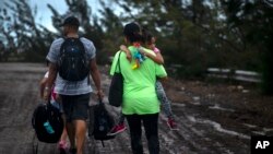 Satu keluarga berjalan setelah diselamatkan dari banjir akibat Badai Dorian, dekat Freeport, Grand Bahama, Bahamas, Selasa, 3 September 2019.