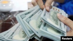 An employee of a bank counts US dollar notes at a branch in Hanoi, Vietnam May 16, 2016.