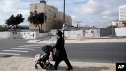 Un hombre pasa frente a la oficina del primer ministro en Jerusalén mientras el gabinete de seguridad de Israel se reúne para decidir si aprueba un acuerdo que liberaría a docenas de rehenes, el viernes 17 de enero de 2025. (Foto AP/Mahmoud Illean)