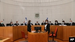 A panel of 11 Israeli Supreme Court judges wearing face masks hear arguments against the legality of Prime Minister Benjamin Netanyahu’s coalition deal, at the Israeli Supreme Court in Jerusalem, May 4, 2020.