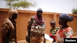 Malian Armed Forces (FAMa) soldiers speak with a woman during the Operation Barkhane in Ndaki, Mali, July 29, 2019. 