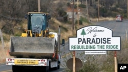 Vehicles pass a sign welcoming people to Paradise, Calif., Nov. 5, 2019. The sign also displays the slogan, "Rebuilding The Ridge," that has become the community's rallying cry since a wildfire devastated the area.