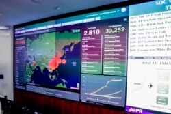 A large monitor displaying a map of Asia and a tally of total coronavirus cases, deaths, and recovered, is visible as Vice President Mike Pence and Health and Human Services Secretary Alex Azar tour the Secretary's Operations Center