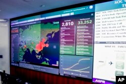 A large monitor displaying a map of Asia and a tally of total coronavirus cases, deaths, and recovered, is visible as Vice President Mike Pence and Health and Human Services Secretary Alex Azar tour the Secretary's Operations Center
