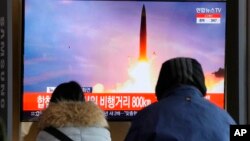 People watch a TV showing a file image of North Korea's missile launch during a news program at the Seoul Railway Station in Seoul, South Korea, Jan. 30, 2022.