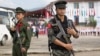 This photo taken on July 28, 2016 shows two Myanmar armed rebels from the Kachin Independence Army (KIA) securing the compound (behind) where Myanmar ethnic rebel leaders and representatives have gathered for a four-day summit in Mai Ja Yang, the KIA cont