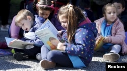 Anak-anak membaca buku cerita di alun-alun Independencia di Montevideo dalam kampanye mendorong kegiatan membaca di tempat umum, 4 September 2015.