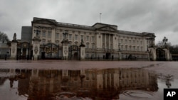 El palacio de Buckingham se refleja el suelo mojado en Londres, el 10 de marzo de 2021.