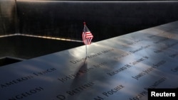 FILE - An American flag is seen left in the engraved names of 9/11 victims at the edge of the north reflecting pool at the 9/11 memorial in lower Manhattan, Sept. 11, 2019.